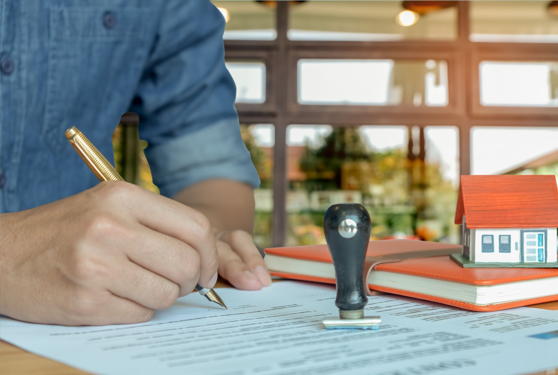 Pen handles signed documents with rubber stamp.model houses, notebook on the table.